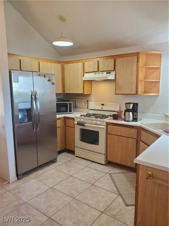 kitchen featuring vaulted ceiling, light tile patterned flooring, appliances with stainless steel finishes, and sink