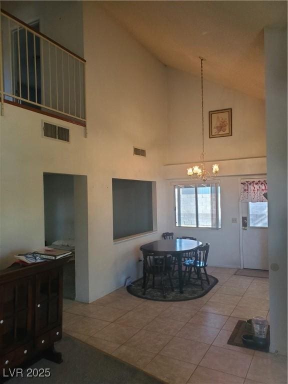 dining area with light tile patterned flooring, a notable chandelier, and high vaulted ceiling