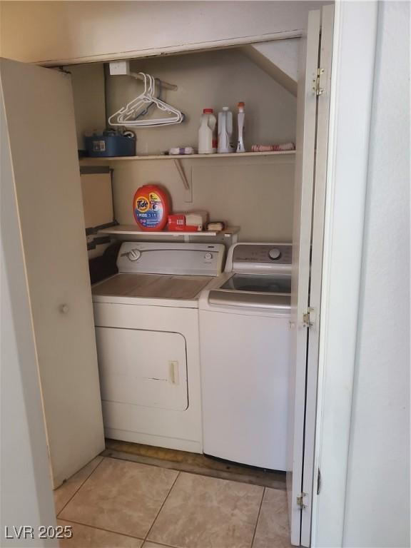 clothes washing area with light tile patterned floors and washer and clothes dryer