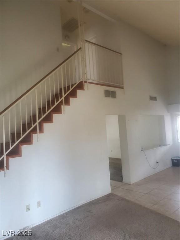 stairs featuring a high ceiling and tile patterned floors