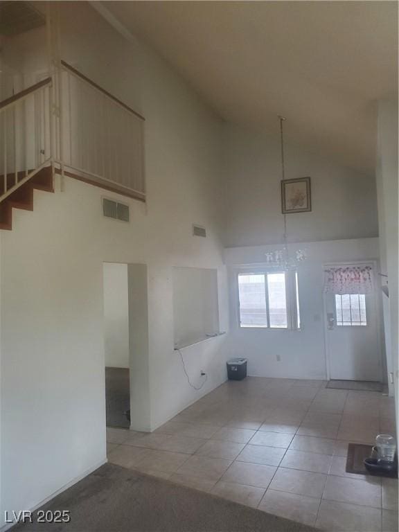 unfurnished living room featuring light tile patterned floors and high vaulted ceiling