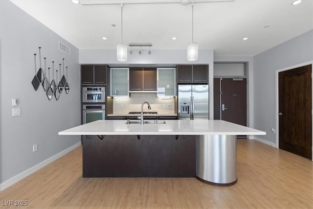 kitchen featuring sink, a breakfast bar area, backsplash, hanging light fixtures, and stainless steel appliances