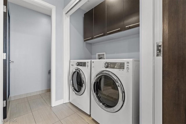 laundry room with cabinets, light tile patterned flooring, and washing machine and clothes dryer