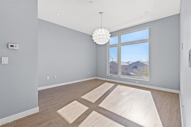 spare room featuring a notable chandelier and wood-type flooring