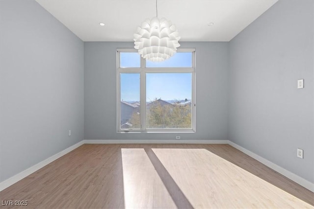 unfurnished room with an inviting chandelier and hardwood / wood-style floors