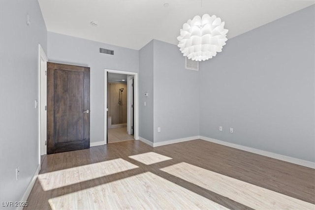 unfurnished room with hardwood / wood-style floors and a notable chandelier