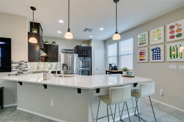 kitchen featuring a kitchen bar, decorative light fixtures, decorative backsplash, and appliances with stainless steel finishes