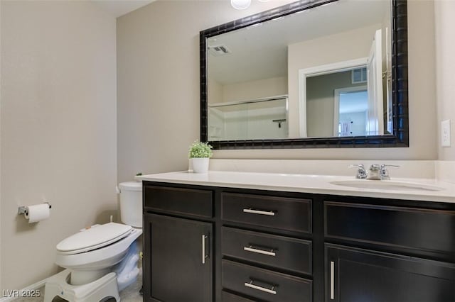 bathroom featuring vanity, a shower with shower door, and toilet