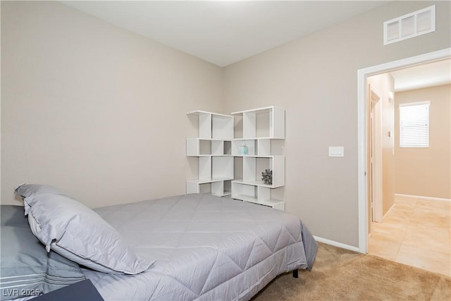 bedroom with baseboards, visible vents, and light colored carpet