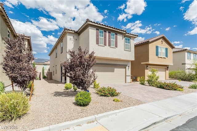 view of front of home with a garage, a tiled roof, decorative driveway, and stucco siding