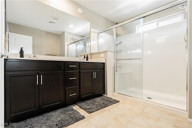 full bathroom featuring double vanity, a stall shower, tile patterned flooring, and visible vents