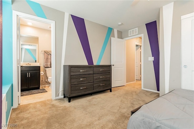 bedroom featuring baseboards, ensuite bathroom, visible vents, and light colored carpet