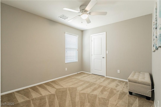 empty room with carpet, visible vents, ceiling fan, and baseboards