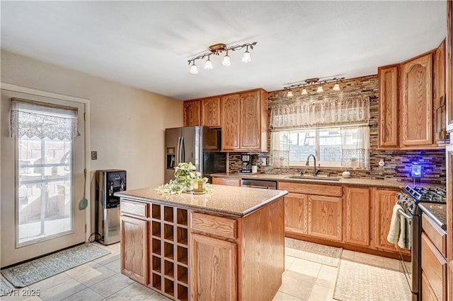 kitchen featuring sink, light stone counters, a kitchen island, stainless steel appliances, and decorative backsplash