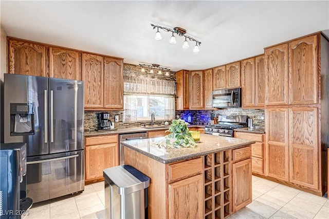 kitchen featuring light stone counters, decorative backsplash, a center island, and appliances with stainless steel finishes