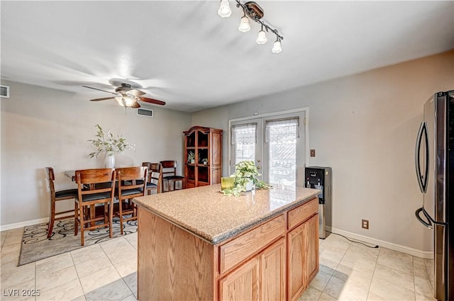 kitchen with a center island, light tile patterned floors, stainless steel fridge, and ceiling fan