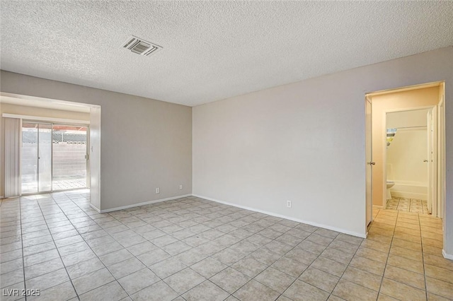 spare room featuring light tile patterned floors and a textured ceiling