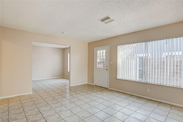 tiled spare room with a textured ceiling