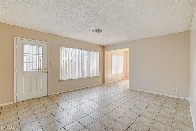 interior space featuring plenty of natural light, a textured ceiling, and light tile patterned flooring