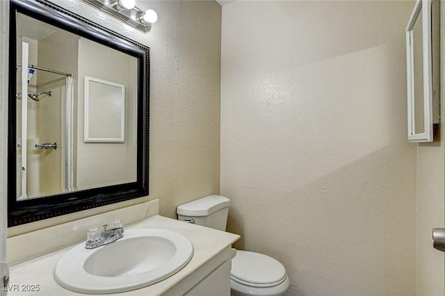 bathroom with walk in shower, vanity, and toilet