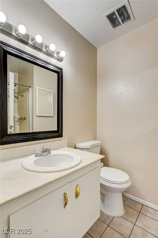 bathroom with vanity, tile patterned floors, toilet, and a shower