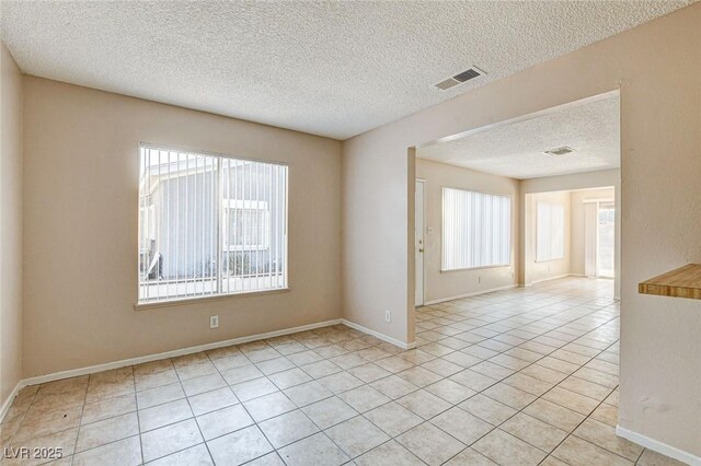 tiled spare room featuring a textured ceiling