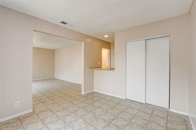 tiled empty room featuring a textured ceiling