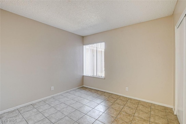 empty room with a textured ceiling and light tile patterned floors