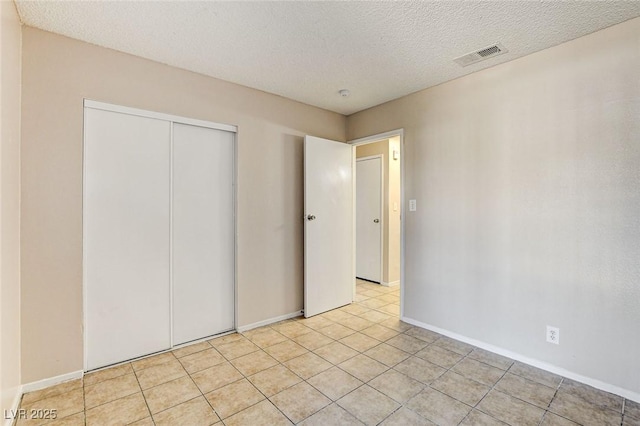 unfurnished bedroom featuring light tile patterned flooring, a closet, and a textured ceiling