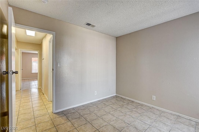 empty room with light tile patterned floors and a textured ceiling