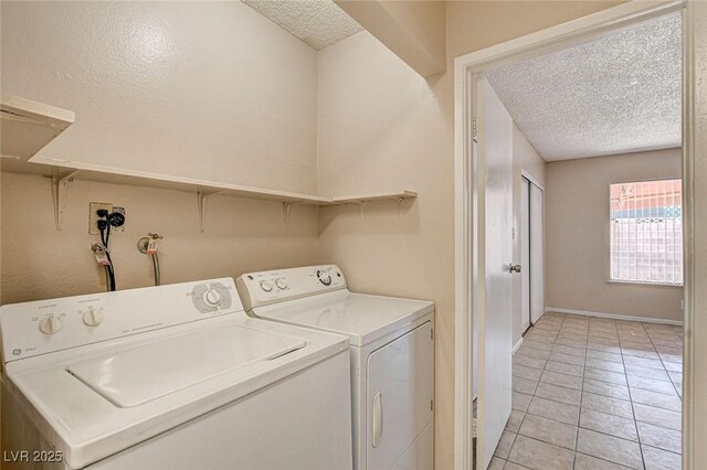 laundry room with washing machine and dryer, a textured ceiling, and light tile patterned flooring