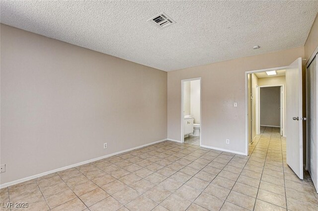 empty room with a textured ceiling and light tile patterned flooring