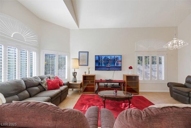 tiled living room featuring a towering ceiling and a chandelier