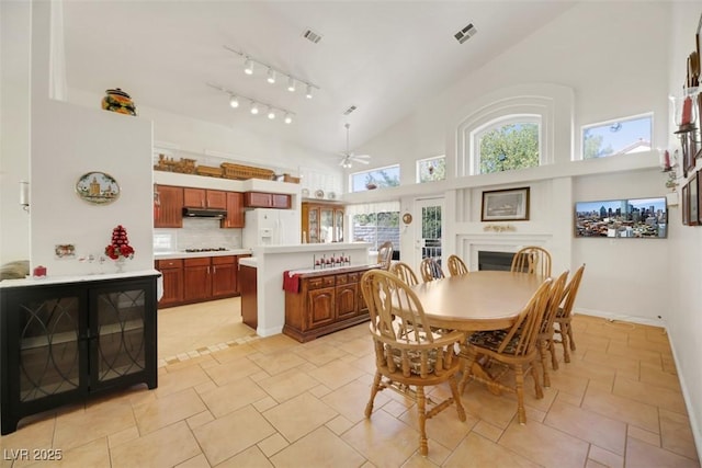 dining room with ceiling fan, track lighting, and high vaulted ceiling