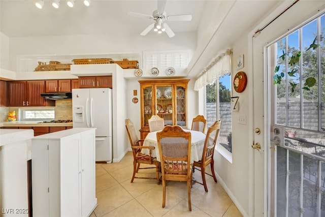 kitchen featuring light tile patterned flooring, white refrigerator with ice dispenser, stainless steel gas cooktop, and decorative backsplash