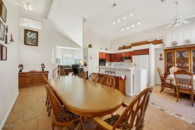 dining space with ceiling fan and high vaulted ceiling