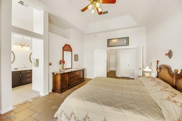 tiled bedroom with ensuite bath, a tray ceiling, and a high ceiling