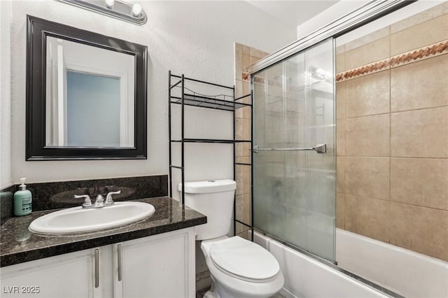 full bathroom with vanity, bath / shower combo with glass door, and toilet