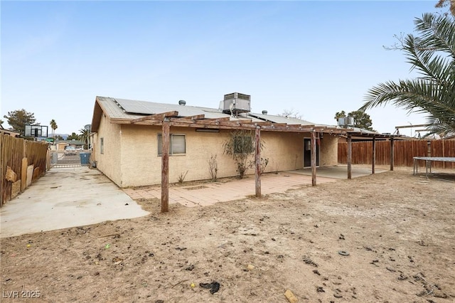 rear view of property with a trampoline, a patio, and solar panels