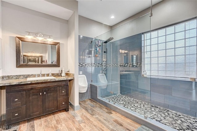 bathroom with hardwood / wood-style flooring, vanity, and a tile shower