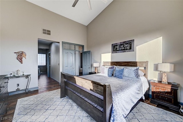 bedroom with ceiling fan, wood-type flooring, high vaulted ceiling, and a closet