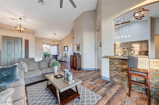 living room with ceiling fan with notable chandelier, high vaulted ceiling, and dark hardwood / wood-style floors