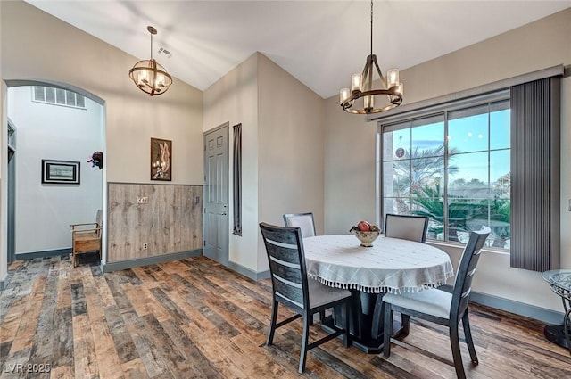 dining space with dark wood-type flooring, vaulted ceiling, and a chandelier