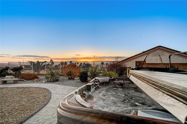 patio terrace at dusk featuring a hot tub