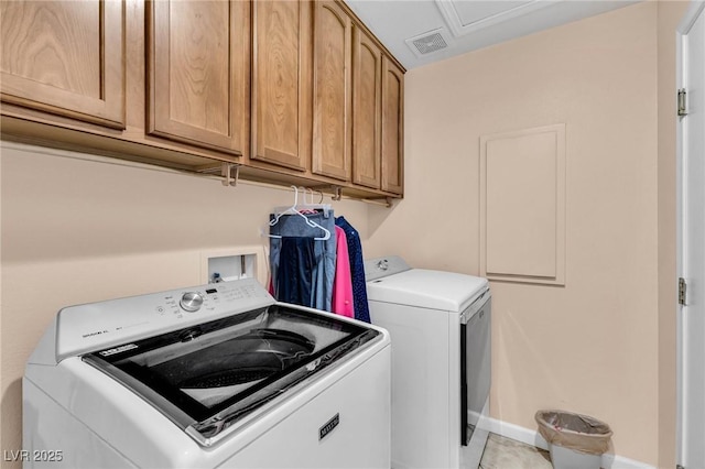 washroom featuring light tile patterned floors, washing machine and dryer, and cabinets