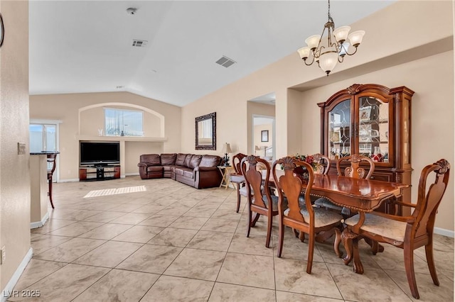 tiled dining area featuring vaulted ceiling and a chandelier