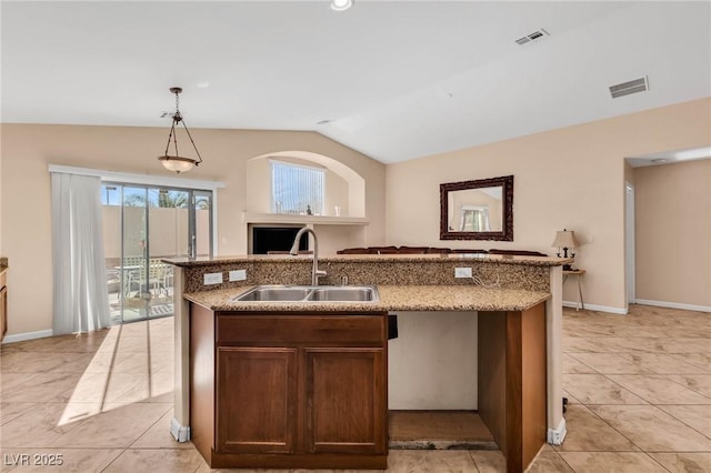 kitchen with light tile patterned flooring, pendant lighting, an island with sink, lofted ceiling, and sink