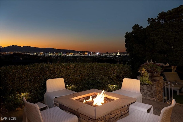 patio terrace at dusk featuring a mountain view and a fire pit