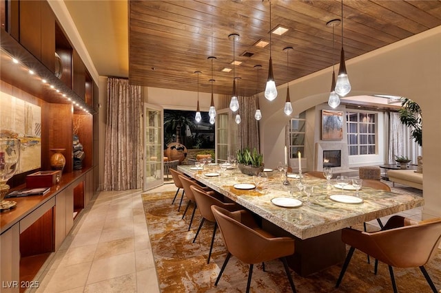 dining room featuring a glass covered fireplace, wooden ceiling, and light tile patterned floors