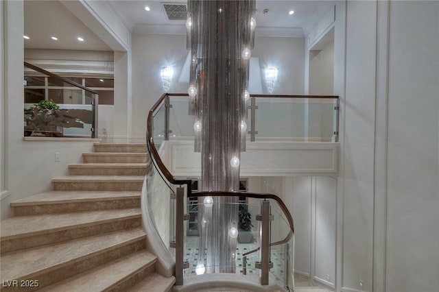 stairs featuring a decorative wall, visible vents, recessed lighting, and crown molding